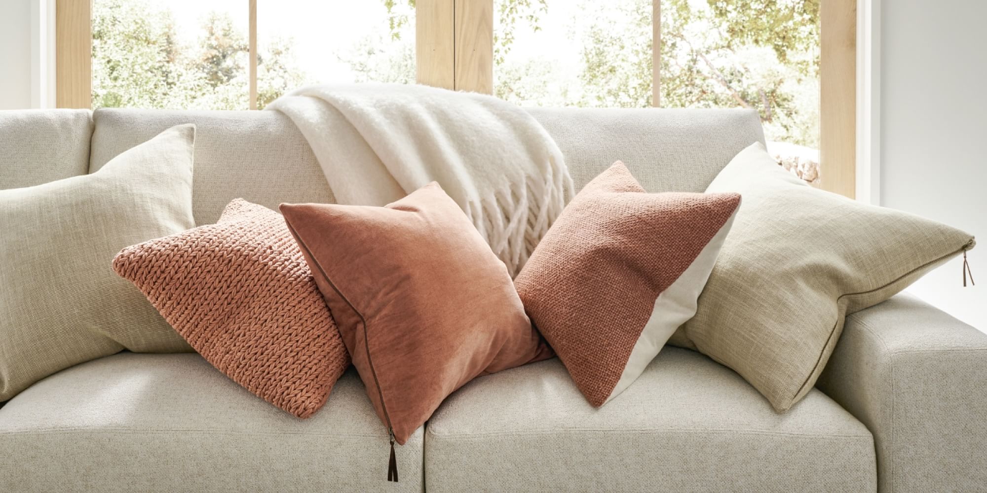 Curtains and a grey sofa, with pillows and a blanket.